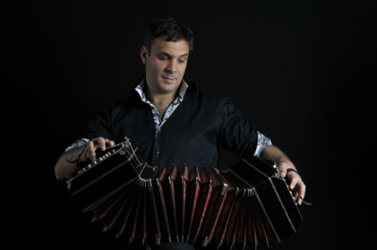 Person spielt Bandoneon vor schwarzem Hintergrund.