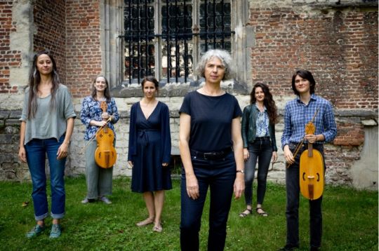 Sechs Personen stehen mit Musikinstrumenten vor einem Backsteingebäude.