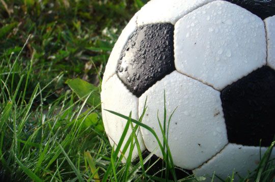 Nahaufnahme eines nassen Fußballs auf Gras.