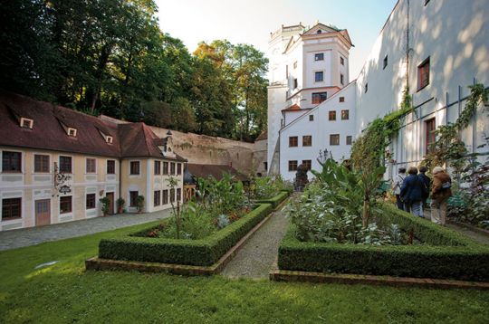 Historische Gebäude und Gärten am Roten Tor in Augsburg unter sonnigem Himmel.