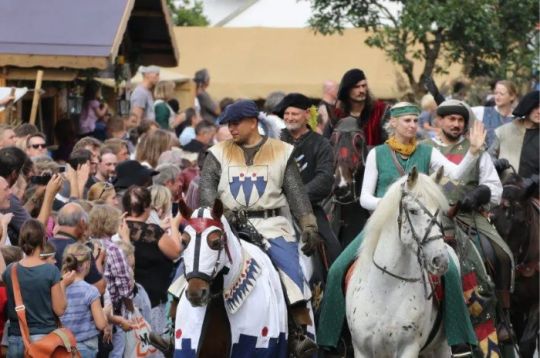Ritter und Publikum bei einem Mittelalterfest in Aichach, mit festlich gekleideten Personen auf Pferden und Zuschauern.