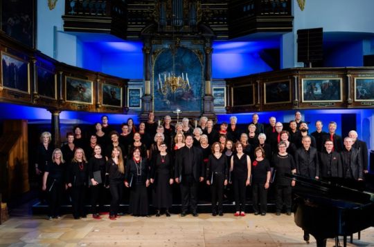 Chor singt in einem prächtigen, mit vielen Zuschauern gefüllten Saal.
