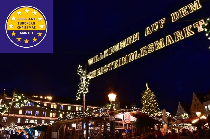 Eingang zum Augsburger Christkindlesmarkt bei Nacht mit festlicher Beleuchtung.