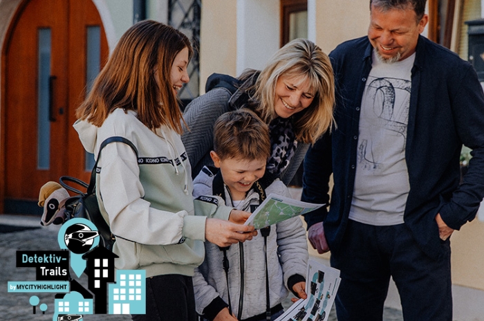 Eine Familie entdeckt freudig eine Karte in einer urbanen Umgebung.