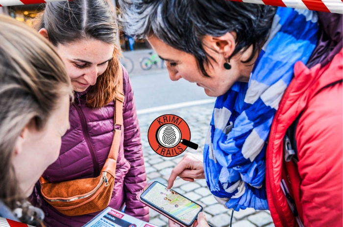 Drei Menschen blicken begeistert auf den Bildschirm eines Smartphones im Freien.